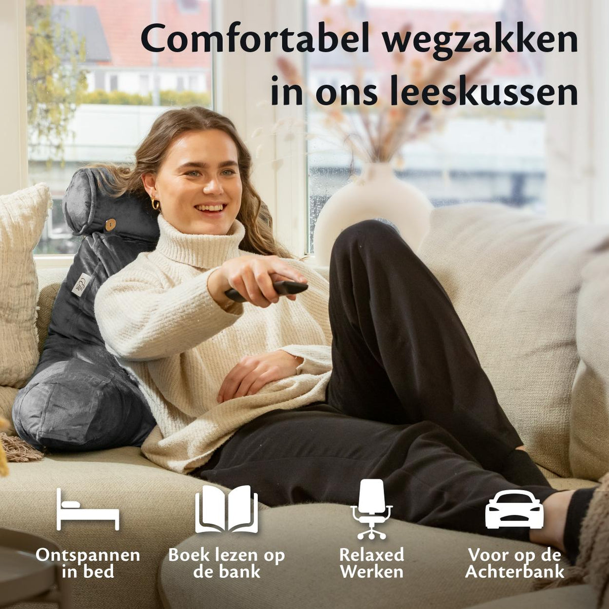 Een vrouw zit ontspannen op de bank met een afstandsbediening in haar hand, genietend van haar tijd met Ella Leeskussen.