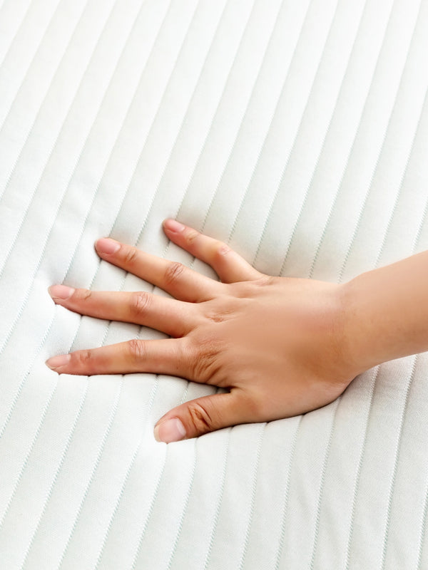 Hand drukt op het gewatteerde witte oppervlak van een Ella matrastopper.