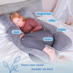 Een vrouw ligt op een bed met een zwangerschapskussen.